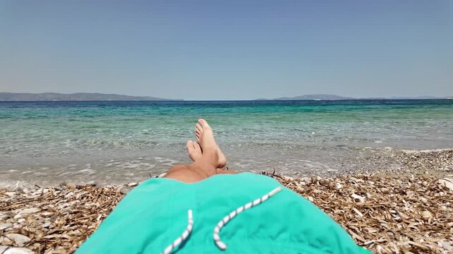 Man sunbathing on a rocky sea ocean beach.