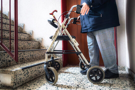 Seniorin steht mit Rollator vor einer Treppe