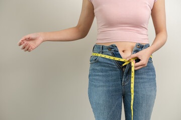 A woman wear fit jeans and measuring her waist