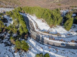 Mountain Road surrounded by snow Viewed from Above with Green Pine Trees and Two Cars