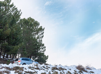 SUV on a Mountain Road Surrounded by Snow Under a Blue Sky with Clouds