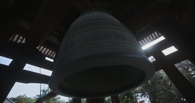 Silhouette beneath old, majestic, massive Japanese bell