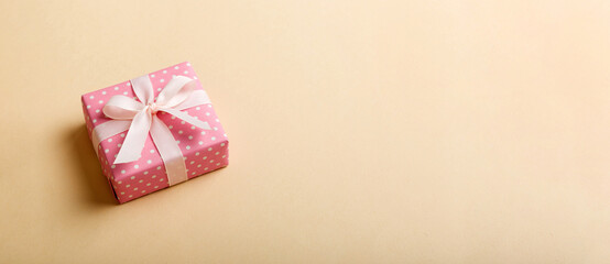 Obraz premium wrapped Christmas or other holiday handmade gift box in color paper with ribbon on colored background. Present box, decoration of gift on colored table, top view with copy space