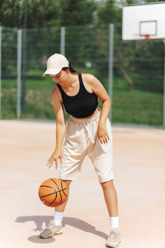 Woman Dribbling Basketball On Outdoor Court. Athletic Movement And Sport Concept.
