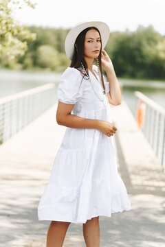 Woman In White Dress On Bridge By Lake. Summer Elegance And Nature.