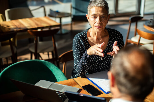 Senior woman leading business consultation in cafe