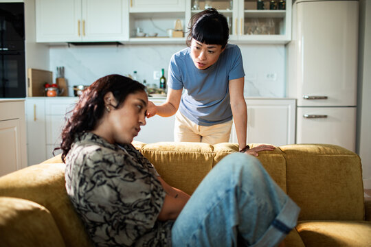 Two women arguing on sofa in home kitchen