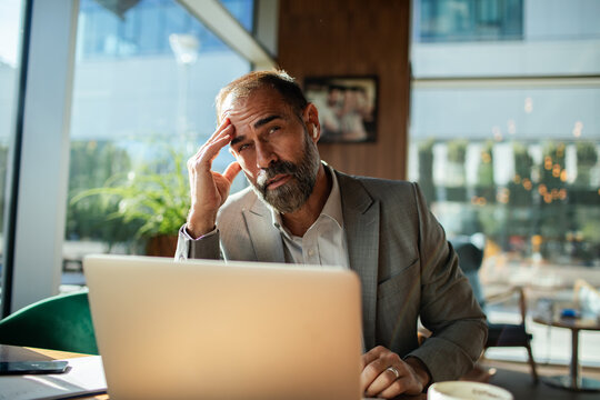 Stressed businessman with laptop in cafe