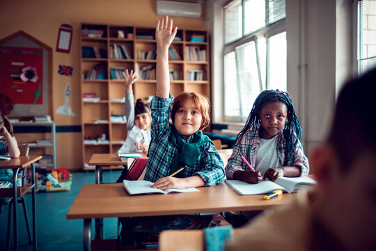 Elementary students raising hands during class at school