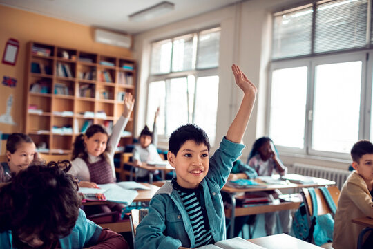 Elementary students raising hands in classroom