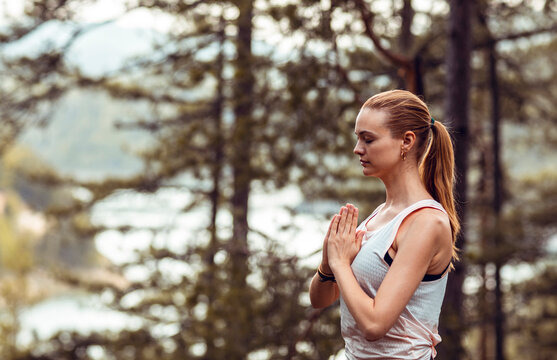 Woman meditating with prayer hands in forest