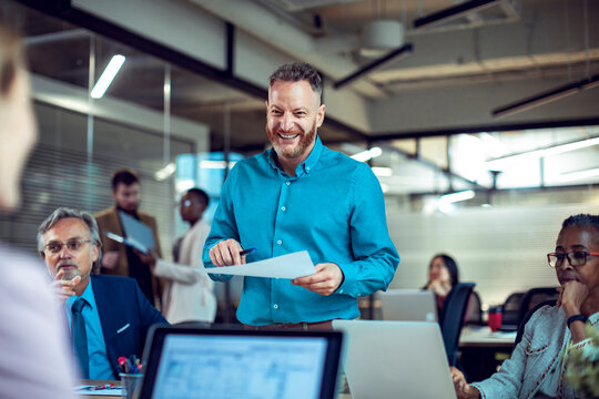 Smiling manager leading team meeting in modern open office