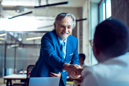 Senior businessman shaking hands in modern office