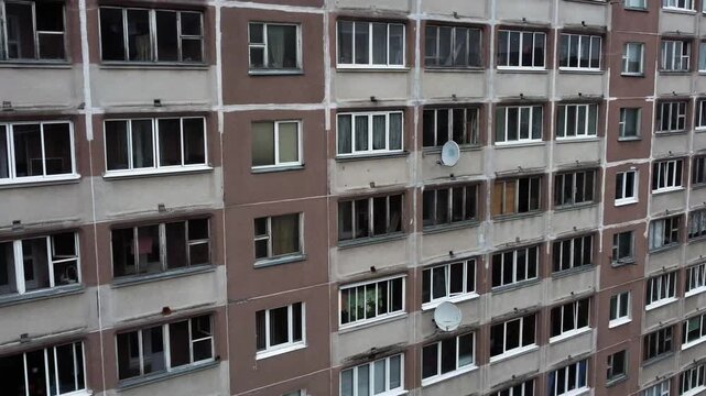 Dirty balconies and the facade of a panel high-rise building.  The facade of an old apartment building with dilapidated window frames. The post-Soviet ghetto.