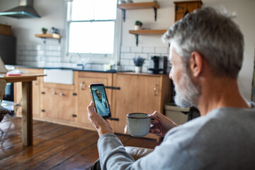 Senior man video calling doctor in home kitchen