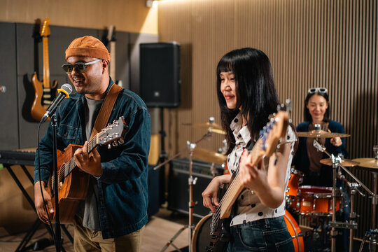 Young asian music group Band members rehearse with instruments guitar bass drum. Teamwork music band practice in studio prepire perform. Vocalist and band