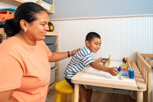 Mother teaches son at home with toys on a table