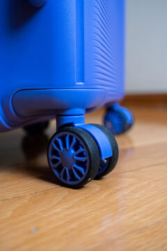 Blue suitcase wheel on wooden floor close-up