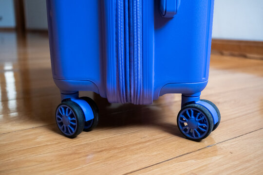 Blue suitcase positioned on a wooden floor with wheels