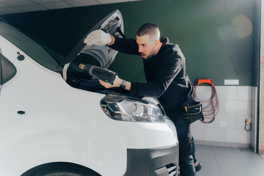 Skilled technician applying vinyl wrap on a vehicle