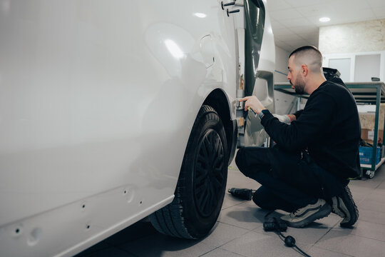 Skilled technician applying vinyl wrap to vehicle door