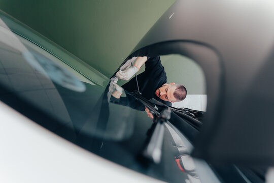 Skilled worker demonstrating car vinyl wrapping technique