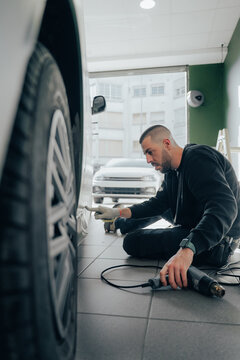 Skilled worker performing car vinyl wrapping process