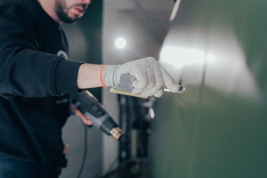 Skilled worker applying vinyl in automotive workshop