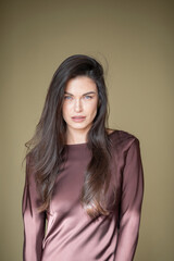 Obraz premium A beautiful brunette girl with a fresh orchid flower in a chocolate-colored dress