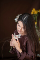 A beautiful brunette girl with a fresh orchid flower in a chocolate-colored dress