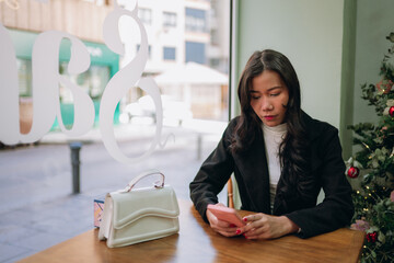 Asian woman using phone at cafe during christmas season