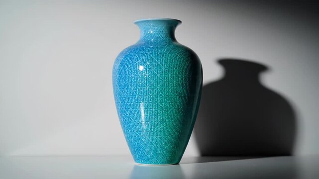 A plain white vase transforms into a vibrant blue and green patterned artwork. Dynamic colors and intricate designs emerge, creating a stunning visual display.