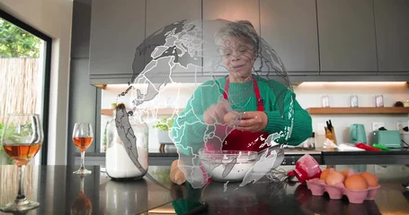 Fotobehang Koken Cracking senior cook in green sweater, red apron making eggs into bowl on island, whisk  © vectorfusionart