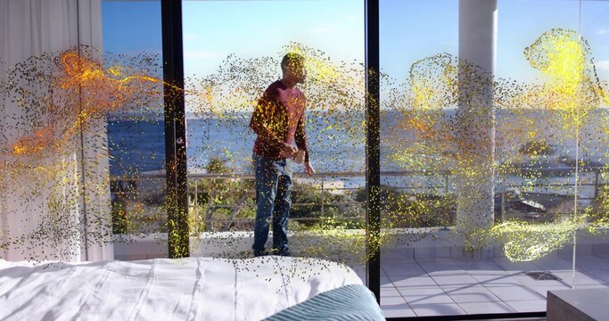 Standing woman in red top and jeans holding device on balcony, bed, glass doors, golden flecks