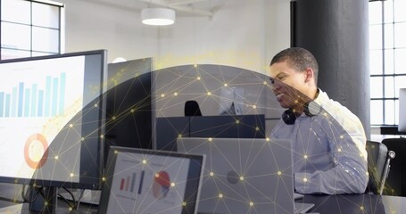 Viewing worker in shirt with headset reviewing charts on office screens network overlay, copy space