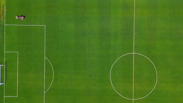 Aerial view of lawn mower working on Gigante de Arroyito football pitch in Rosario, Argentina. The camera performs a crane down movement with travelling following the grass cutting machine across gree