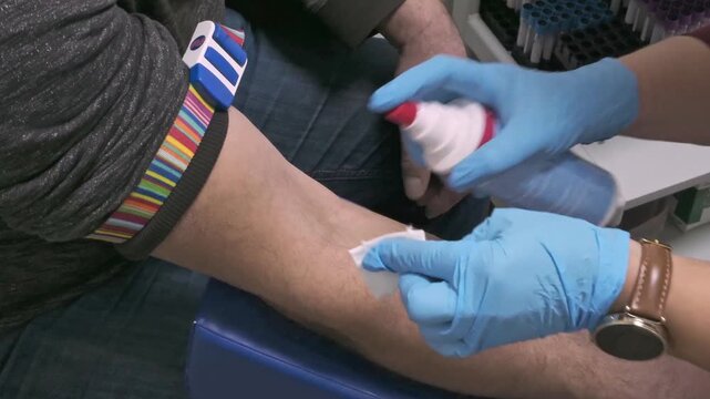 Close-up of gloved hands disinfecting patients before blood sampling. Preventive heals check and blood donation concept.