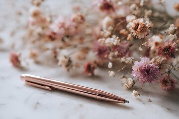 Elegant pink roses and decorative pen on a soft cloth backdrop.