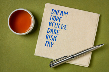 dream, hope, believe, dare, risk, try - motivational words on a napkin with tea