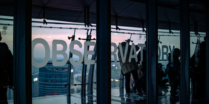 Observation deck window with Observatory sign and city view during blue hour dusk