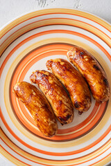 Glazed chicken sausages arranged on decorative plate with warm caramelized finish