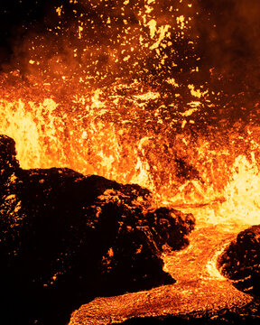 Aerial view of molten fury erupts, painting the sky with fiery hues and casting long shadows across the rugged landscape, Reykjavikurborg, Iceland.