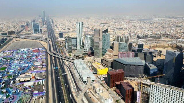 Breathtaking aerial panoramic view of the evolving Riyadh skyline, featuring the vast green expanse of King Salman Park alongside iconic landmarks, the Kingdom Centre, King Abdullah Financial District