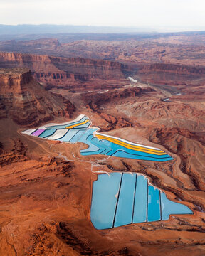 Aerial view of vibrant evaporation ponds shimmer amid the rusty canyons near Moab, Utah, United States.