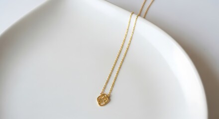 Fototapeta premium Simple Minimalist Gold Knot Pendant Necklace on White Elegant Plate