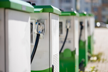 Row of electric vehicle charging stations with plugged-in connector and cable.