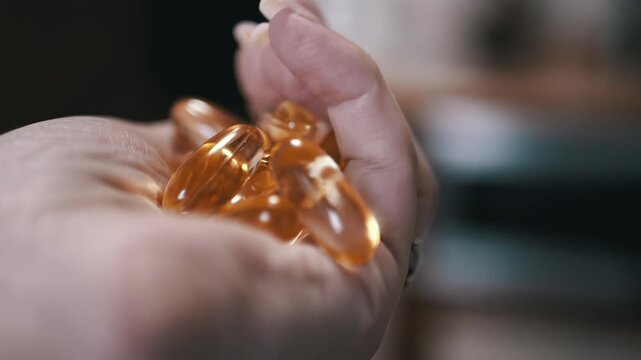 A hand holds a collection of golden fish oil capsules, highlighting their role in a healthy lifestyle. Great for supplement and wellness content.