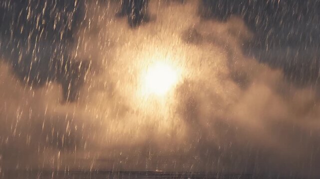 Golden sunbeams pierce through heavy rain, illuminating a misty, atmospheric landscape