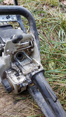 Chainsaw with open casing on grass shows internal structure and maintenance needs during autumn