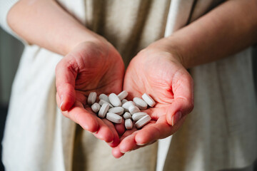 Woman's hands holding a pile of pills and capsules. Prescription medication, treatment sickness concept